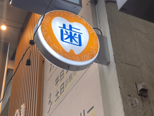 突き出し看板・袖看板施工事例写真 東京都 オレンジの背景に歯のイラストがある目立つ看板