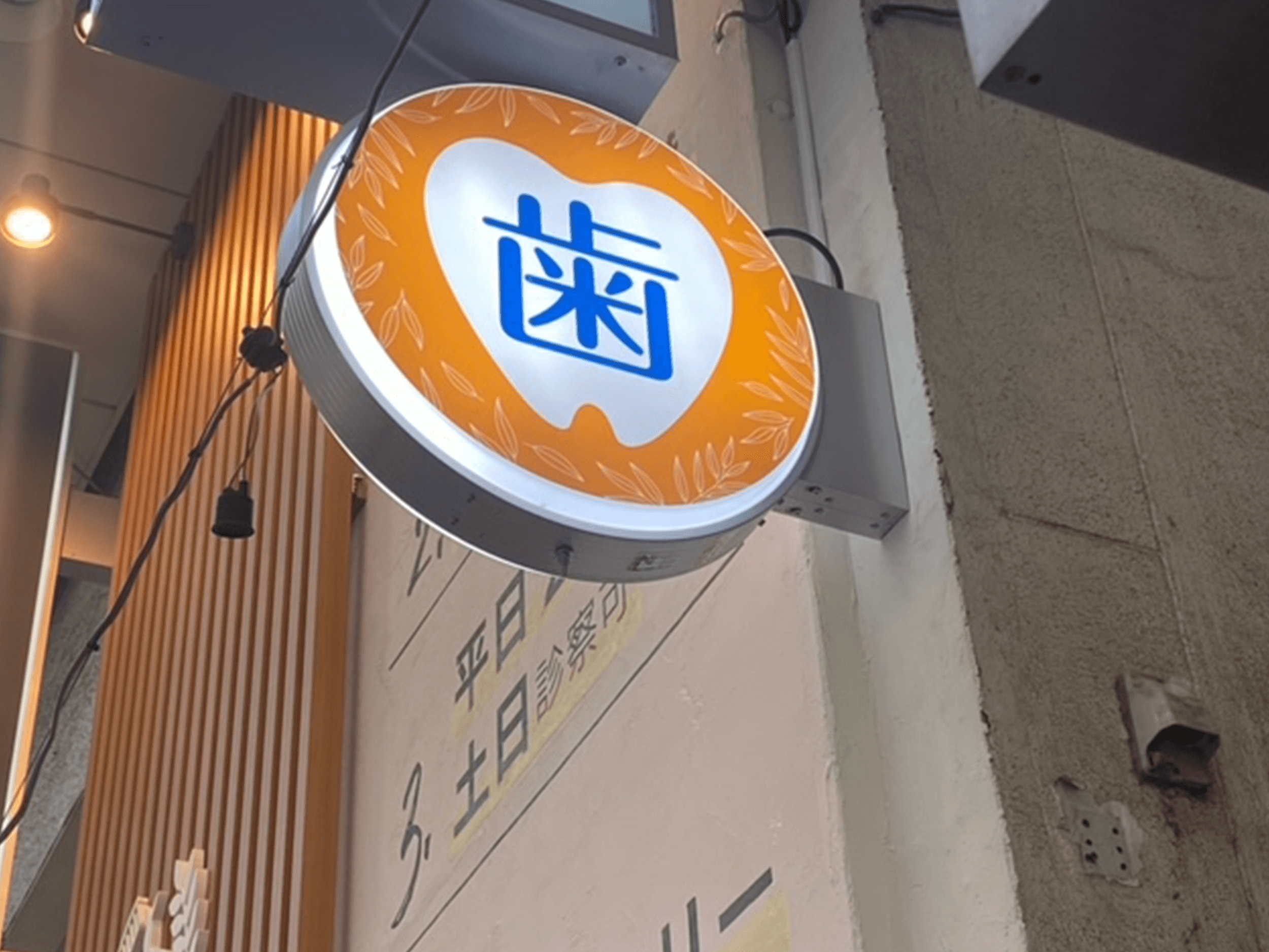 突き出し看板・袖看板施工事例写真 東京都 オレンジの背景に歯のイラストがある目立つ看板